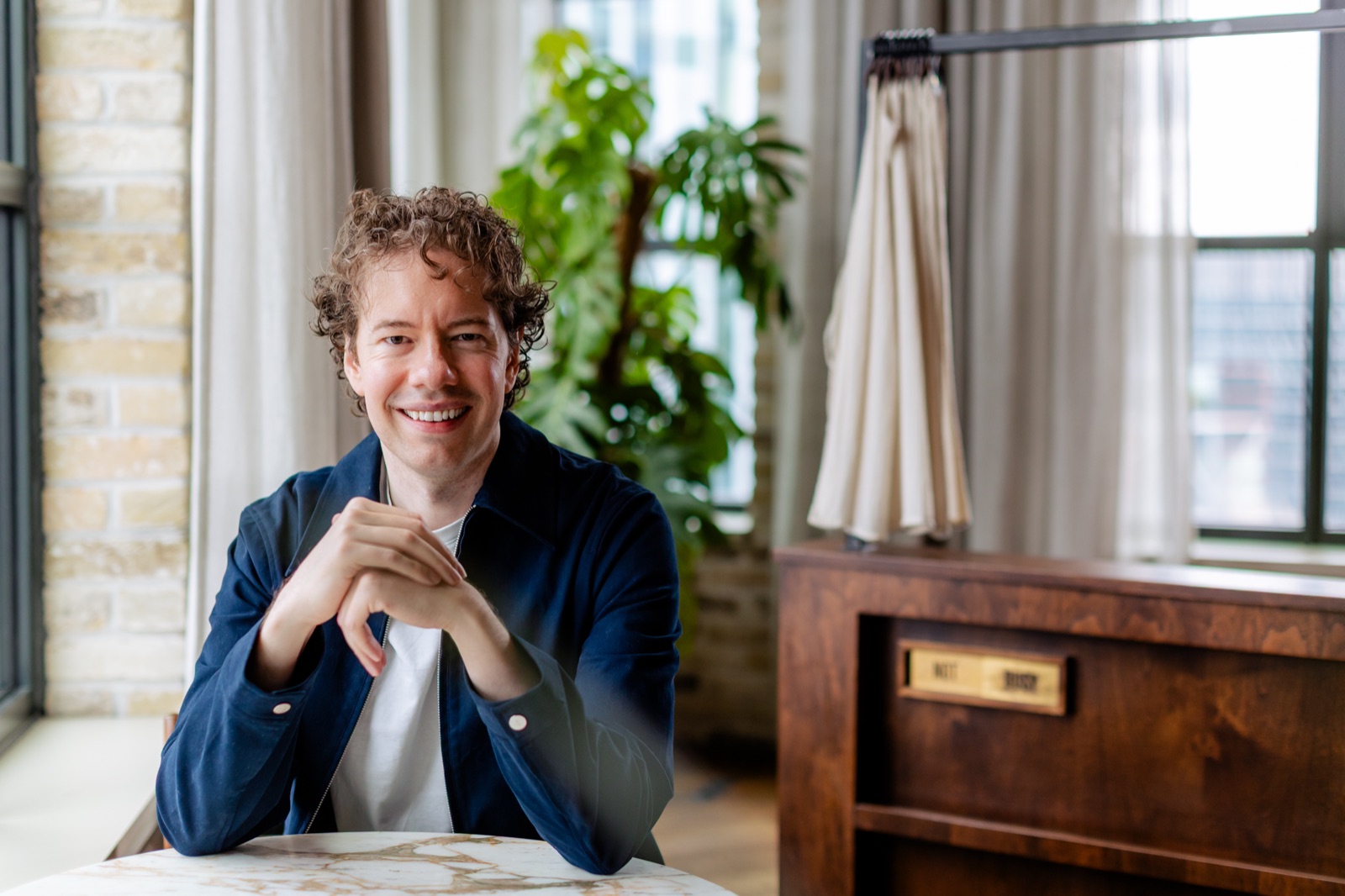 Michael Ashcroft, smiling, sitting at a marble table in a bright room